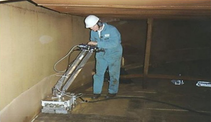 Technician scanning a storage-tank floor for corrosion mapping.